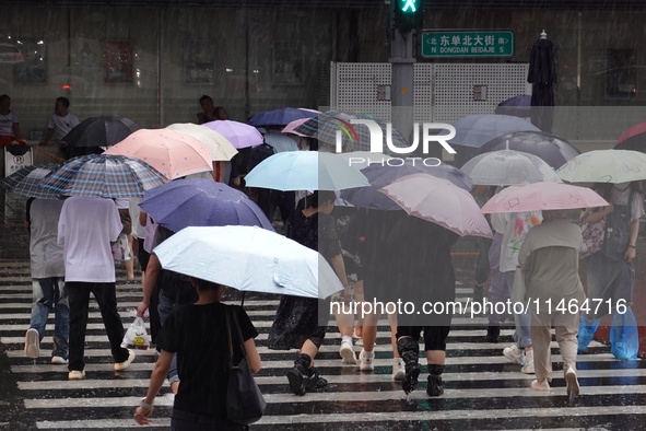 Pedestrians are walking during a rainstorm in Beijing, China, on August 9, 2024. 