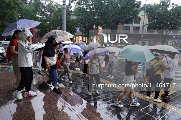 Pedestrians are walking during a rainstorm in Beijing, China, on August 9, 2024. 