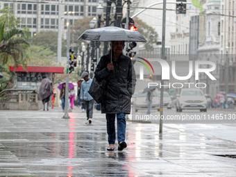 Pedestrians are protecting themselves from the rain in the central region of Sao Paulo, Brazil, on Friday, August 9. (