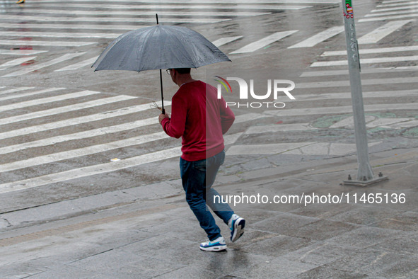 Pedestrians are protecting themselves from the rain in the central region of Sao Paulo, Brazil, on Friday, August 9. 