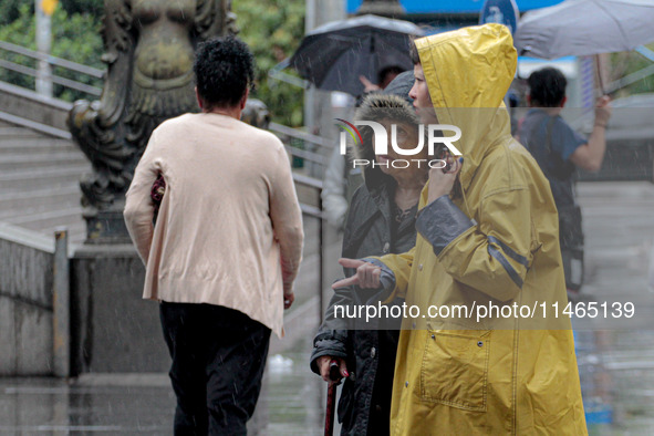 Pedestrians are protecting themselves from the rain in the central region of Sao Paulo, Brazil, on Friday, August 9. 