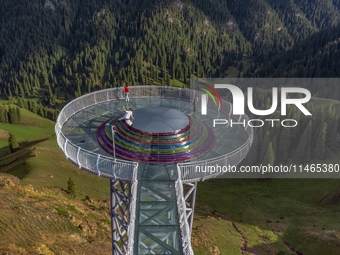 Tourists are experiencing a glass walkway at Pingding Mountain Scenic area in Mulei Kazak Autonomous county, Changji Hui Autonomous prefectu...