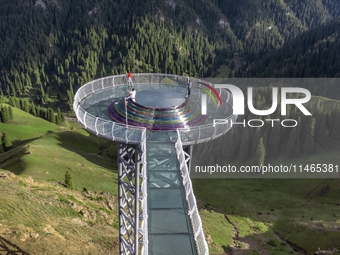 Tourists are experiencing a glass walkway at Pingding Mountain Scenic area in Mulei Kazak Autonomous county, Changji Hui Autonomous prefectu...