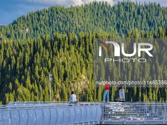 Tourists are experiencing a glass walkway at Pingding Mountain Scenic area in Mulei Kazak Autonomous county, Changji Hui Autonomous prefectu...