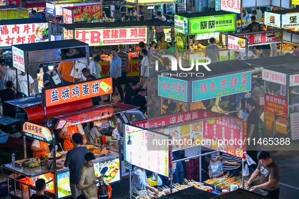 People are tasting food at the illuminated Longhu Zijin Night Market in Nanjing, China, on August 9, 2024. 