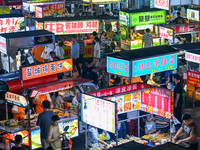 People are tasting food at the illuminated Longhu Zijin Night Market in Nanjing, China, on August 9, 2024. (