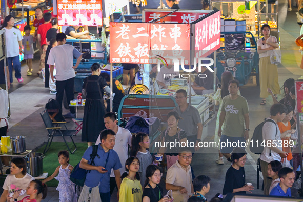 People are tasting food at the illuminated Longhu Zijin Night Market in Nanjing, China, on August 9, 2024. 