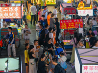 People are tasting food at the illuminated Longhu Zijin Night Market in Nanjing, China, on August 9, 2024. (