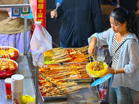 People are tasting food at the illuminated Longhu Zijin Night Market in Nanjing, China, on August 9, 2024. (