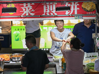 People are tasting food at the illuminated Longhu Zijin Night Market in Nanjing, China, on August 9, 2024. (