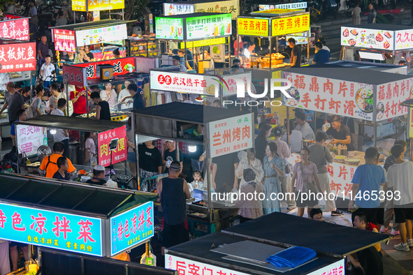 People are tasting food at the illuminated Longhu Zijin Night Market in Nanjing, China, on August 9, 2024. 