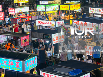 People are tasting food at the illuminated Longhu Zijin Night Market in Nanjing, China, on August 9, 2024. (