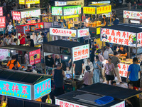 People are tasting food at the illuminated Longhu Zijin Night Market in Nanjing, China, on August 9, 2024. (