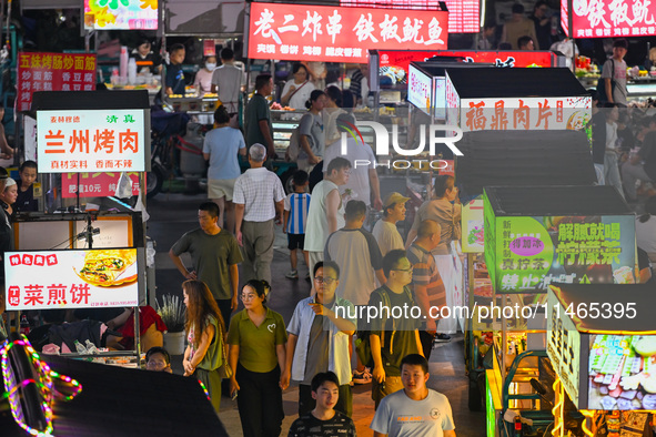 People are tasting food at the illuminated Longhu Zijin Night Market in Nanjing, China, on August 9, 2024. 