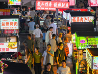 People are tasting food at the illuminated Longhu Zijin Night Market in Nanjing, China, on August 9, 2024. (