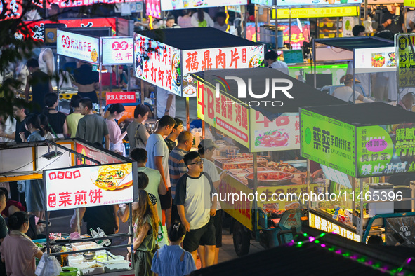 People are tasting food at the illuminated Longhu Zijin Night Market in Nanjing, China, on August 9, 2024. 