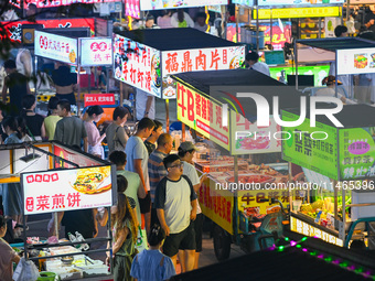 People are tasting food at the illuminated Longhu Zijin Night Market in Nanjing, China, on August 9, 2024. (