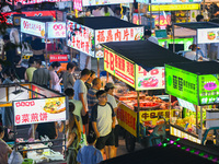 People are tasting food at the illuminated Longhu Zijin Night Market in Nanjing, China, on August 9, 2024. (