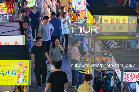 People are tasting food at the illuminated Longhu Zijin Night Market in Nanjing, China, on August 9, 2024. 