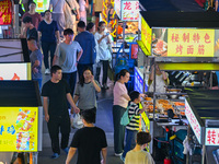 People are tasting food at the illuminated Longhu Zijin Night Market in Nanjing, China, on August 9, 2024. (