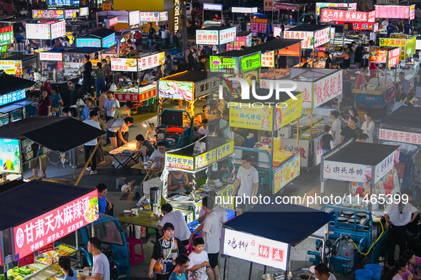 People are tasting food at the illuminated Longhu Zijin Night Market in Nanjing, China, on August 9, 2024. 