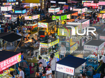 People are tasting food at the illuminated Longhu Zijin Night Market in Nanjing, China, on August 9, 2024. (