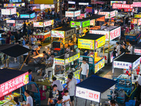 People are tasting food at the illuminated Longhu Zijin Night Market in Nanjing, China, on August 9, 2024. (