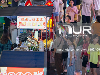 People are tasting food at the illuminated Longhu Zijin Night Market in Nanjing, China, on August 9, 2024. (