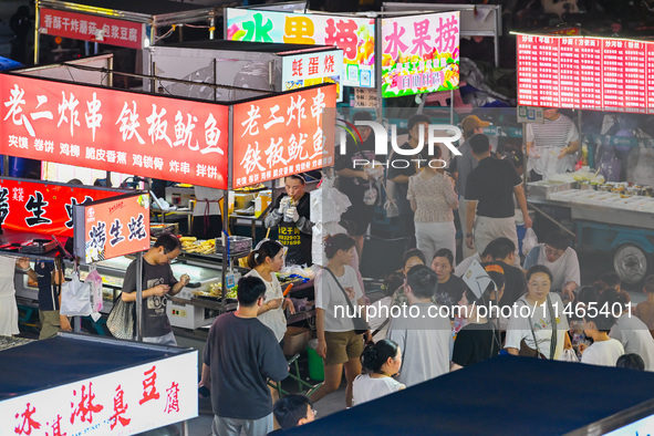 People are tasting food at the illuminated Longhu Zijin Night Market in Nanjing, China, on August 9, 2024. 