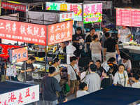 People are tasting food at the illuminated Longhu Zijin Night Market in Nanjing, China, on August 9, 2024. (