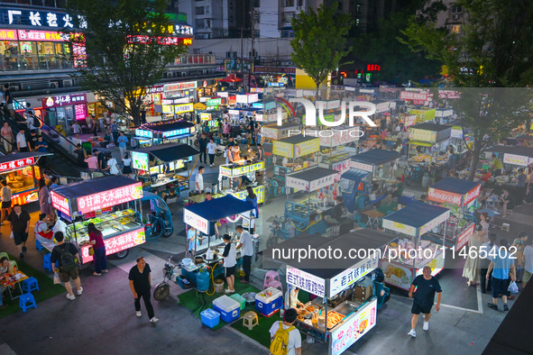 People are tasting food at the illuminated Longhu Zijin Night Market in Nanjing, China, on August 9, 2024. 