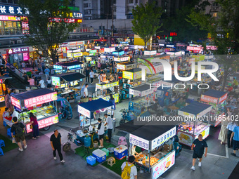 People are tasting food at the illuminated Longhu Zijin Night Market in Nanjing, China, on August 9, 2024. (