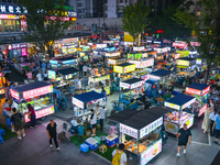 People are tasting food at the illuminated Longhu Zijin Night Market in Nanjing, China, on August 9, 2024. (