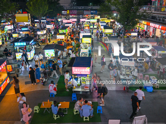 People are tasting food at the illuminated Longhu Zijin Night Market in Nanjing, China, on August 9, 2024. (