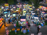 People are tasting food at the illuminated Longhu Zijin Night Market in Nanjing, China, on August 9, 2024. (