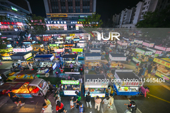 People are tasting food at the illuminated Longhu Zijin Night Market in Nanjing, China, on August 9, 2024. 