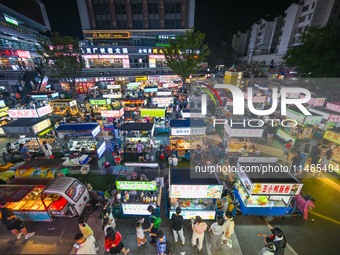 People are tasting food at the illuminated Longhu Zijin Night Market in Nanjing, China, on August 9, 2024. (