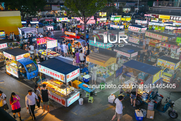 People are tasting food at the illuminated Longhu Zijin Night Market in Nanjing, China, on August 9, 2024. 