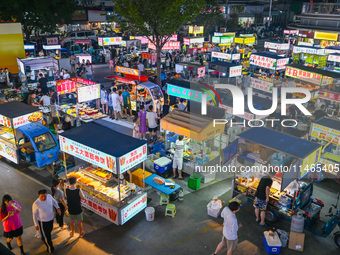 People are tasting food at the illuminated Longhu Zijin Night Market in Nanjing, China, on August 9, 2024. (