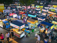 People are tasting food at the illuminated Longhu Zijin Night Market in Nanjing, China, on August 9, 2024. (