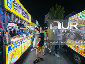 People are tasting food at the illuminated Longhu Zijin Night Market in Nanjing, China, on August 9, 2024. (