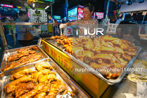 People are tasting food at the illuminated Longhu Zijin Night Market in Nanjing, China, on August 9, 2024. 