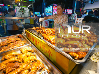 People are tasting food at the illuminated Longhu Zijin Night Market in Nanjing, China, on August 9, 2024. (