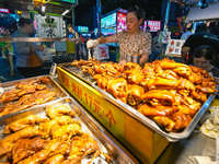 People are tasting food at the illuminated Longhu Zijin Night Market in Nanjing, China, on August 9, 2024. (