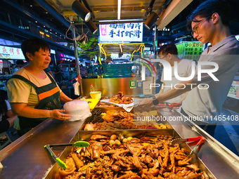 People are tasting food at the illuminated Longhu Zijin Night Market in Nanjing, China, on August 9, 2024. (