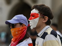 KRAKOW, POLAND - AUGUST 9:
Members of the Belarusian diaspora, wearing masks to maintain anonymity, gather at Krakow's Market Square for the...