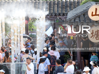 Tourists are waiting to board a boat at a cruise terminal installed with spray cooling devices in Suzhou, China, on August 8, 2024. (