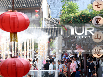 Tourists are waiting to board a boat at a cruise terminal installed with spray cooling devices in Suzhou, China, on August 8, 2024. (