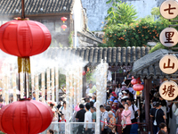 Tourists are waiting to board a boat at a cruise terminal installed with spray cooling devices in Suzhou, China, on August 8, 2024. (