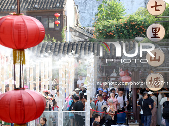 Tourists are waiting to board a boat at a cruise terminal installed with spray cooling devices in Suzhou, China, on August 8, 2024. (